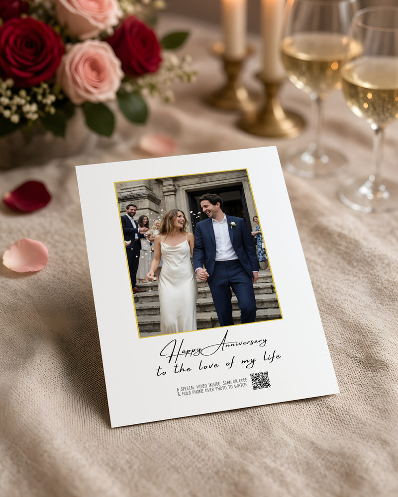 The Forever Card with a couple's wedding photo, on a linen table by candlelight with roses